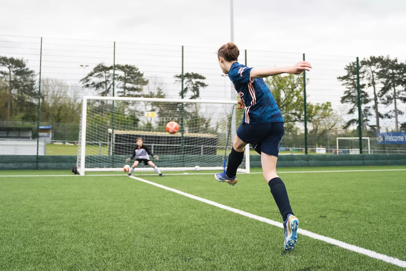 Young footballer striking a shot on goal during a Delta Sports summer football camp session