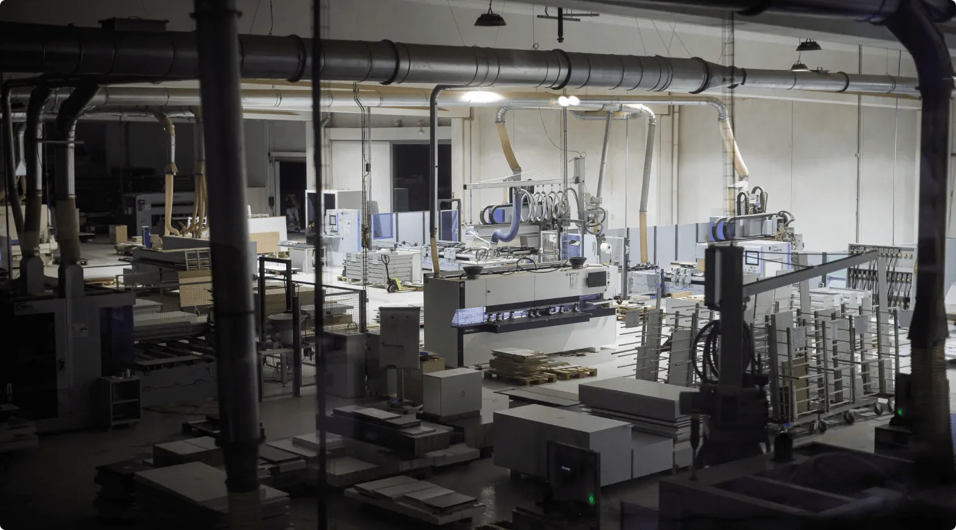 Interior de uma fábrica com máquinas industriais e materiais organizados para produção.