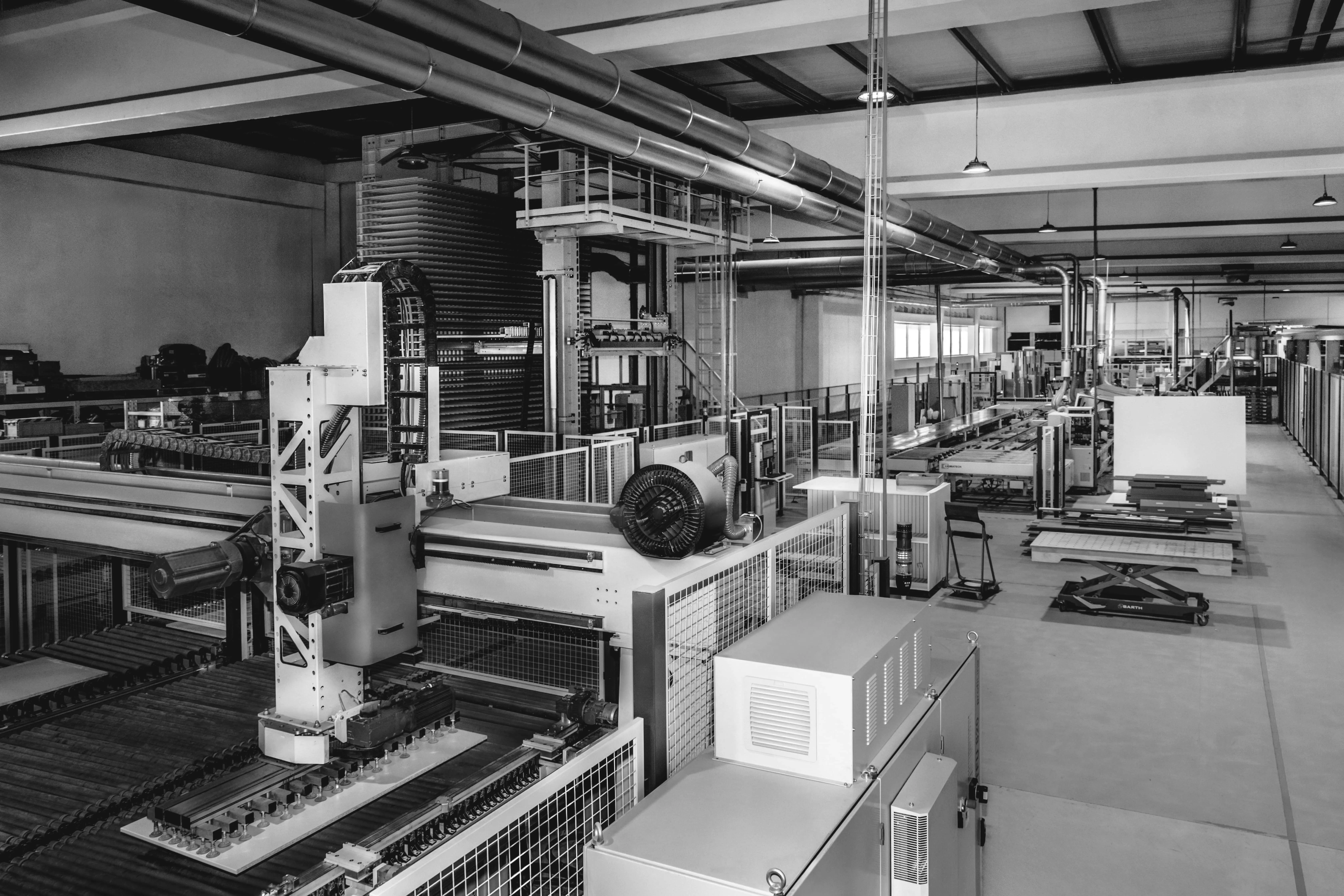 Interior da fábrica com máquinas industriais grandes e equipamentos de produção em linha.