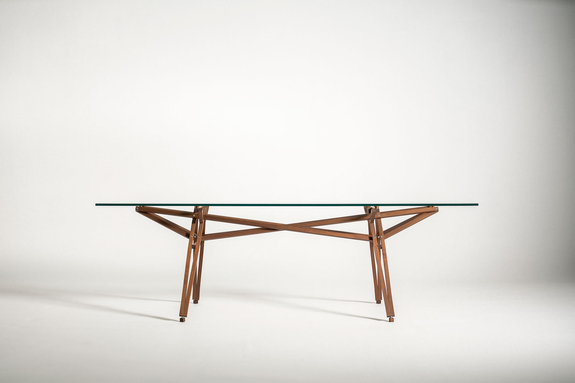 Molino table with a glass top and wooden base, on a white background