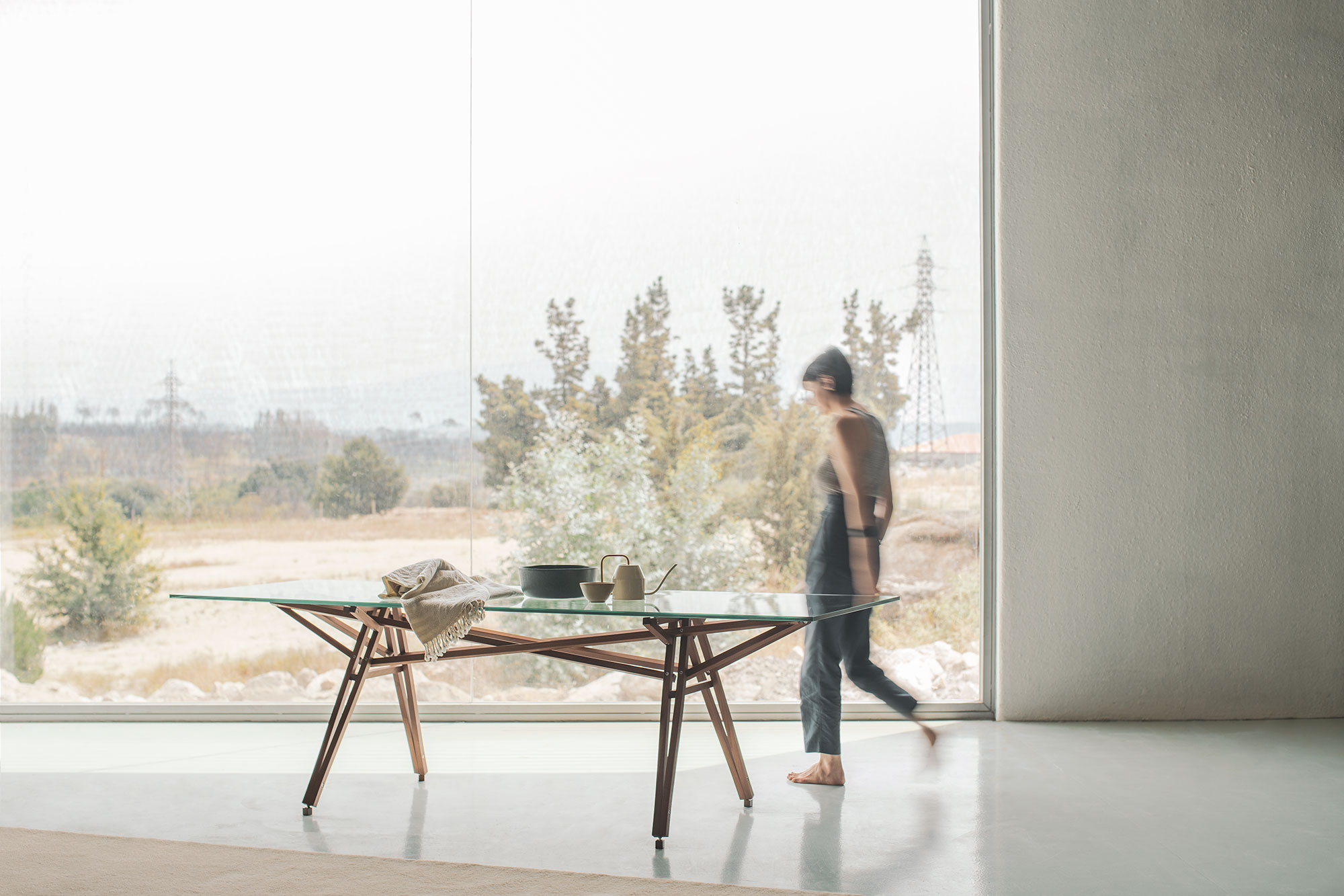 To Molino table in a room with a large window to the outdoors, with a person walking past in the background