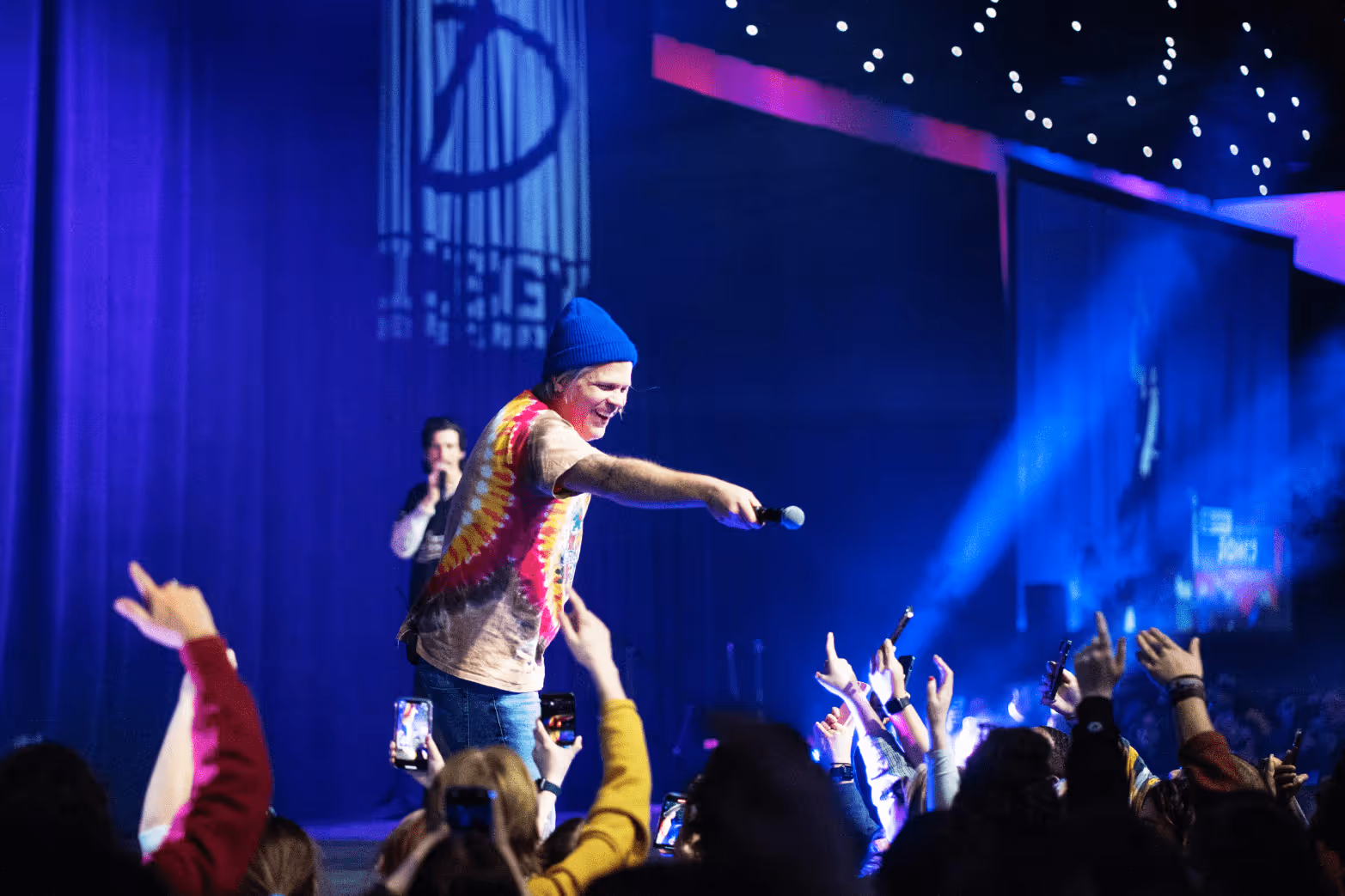 Band performing to a crowd. Singer pointing microphone to audience