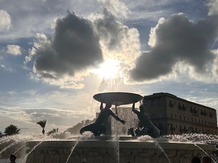 Eine Fontäne im Lichtspiel mit Sonne und Wolken