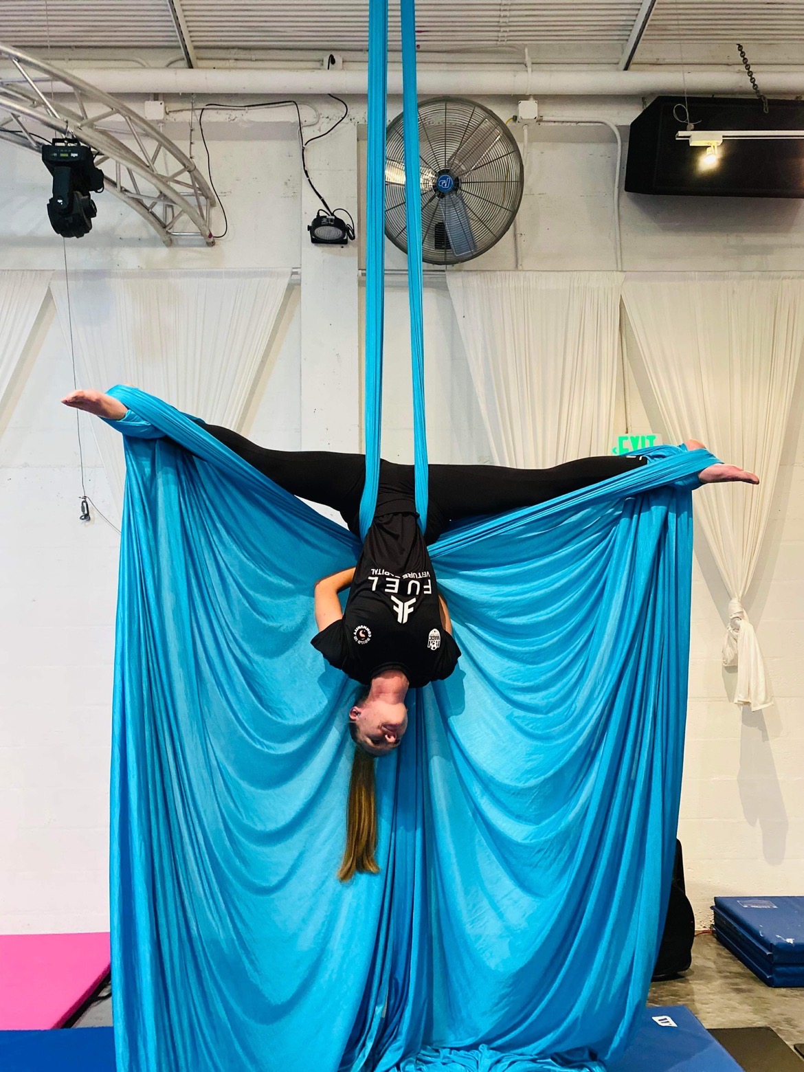 Michelle Bakels, G2i's Developer Health Program Director, is suspended from the ceiling by a silk hammock during an aerial yoga class.