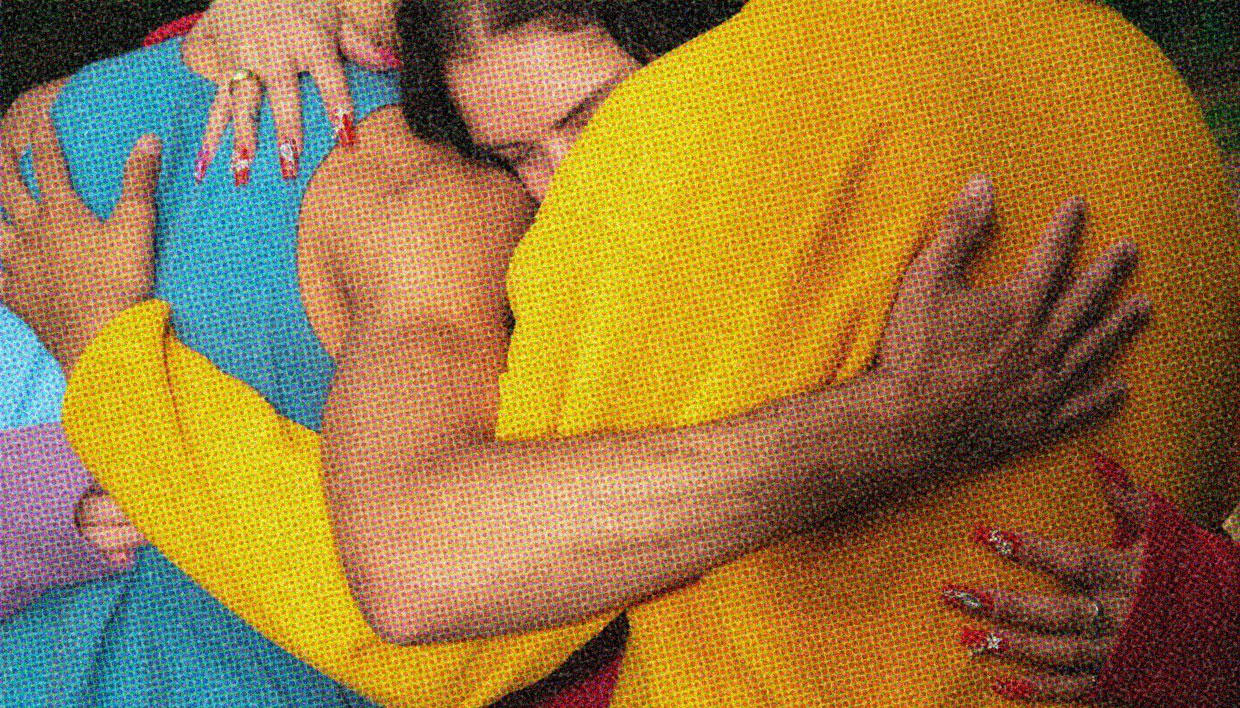 Three people embrace.