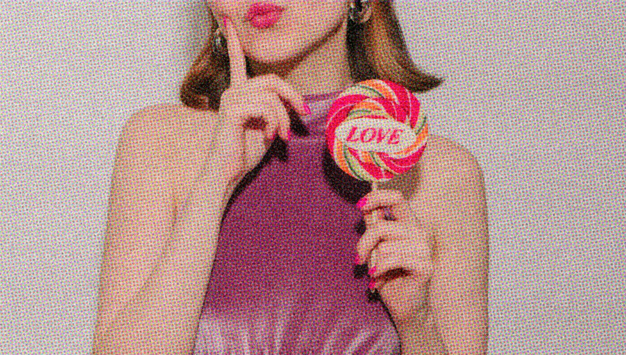 A person holds a large lollipop emblazoned with the word LOVE. 