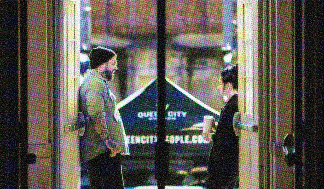 Two people are framed in an open doorway, leaning against opposite sides, conversing casually.