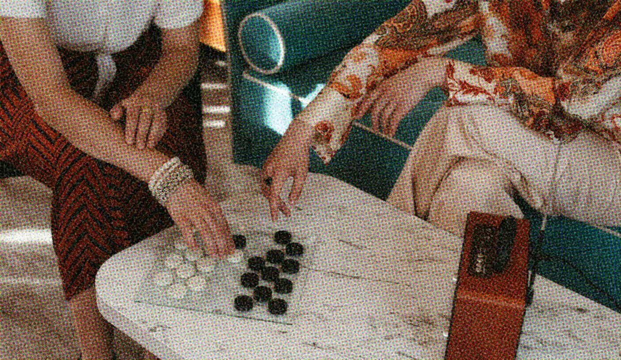 A close-up of two people playing a board game. They're moving the pieces on the board. Perhaps their fingers will touch and they'll feel the sparks?