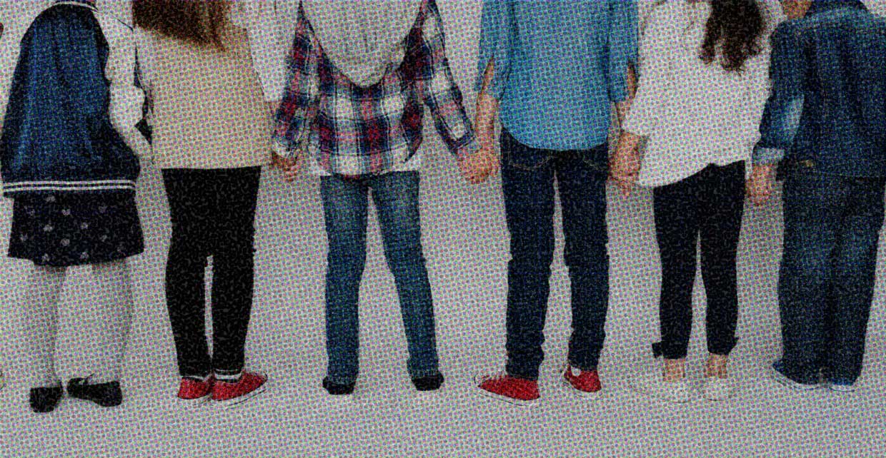 Several people stand together, holding hands.