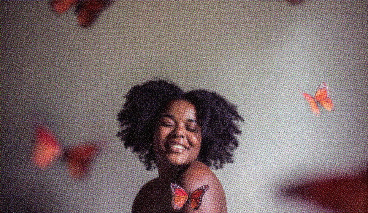 Woman's curly hair frames her face as butterflies gracefully flutter around her.