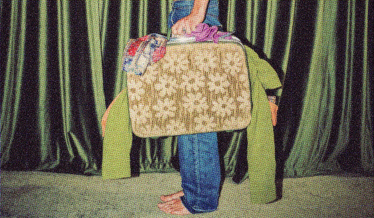 A man holding a luggage case overflowing with clothes.