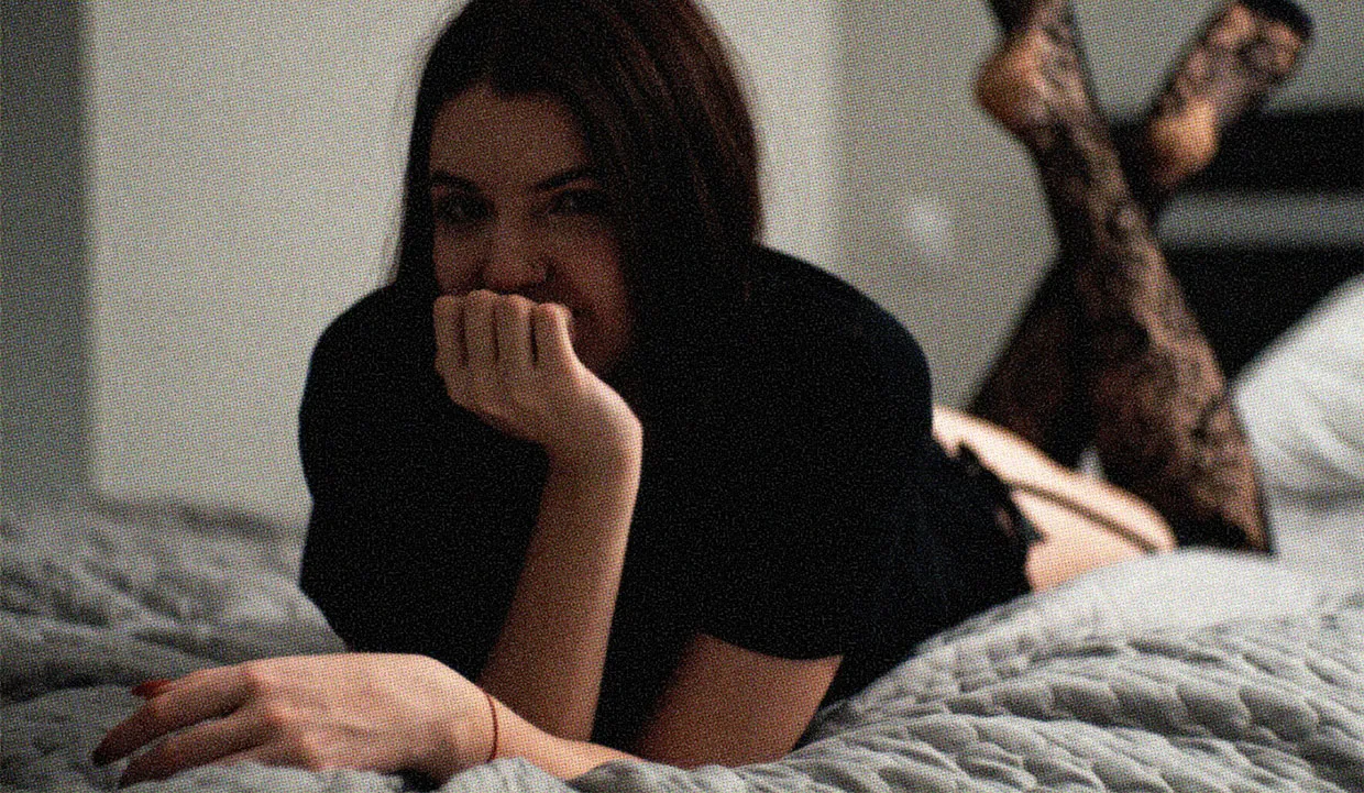 A young woman in lacy stockings relaxing on her bed.