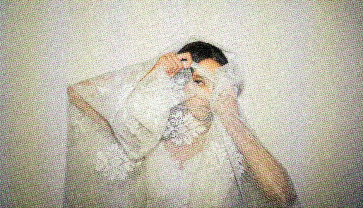A woman peers through a hole in a piece of lace.