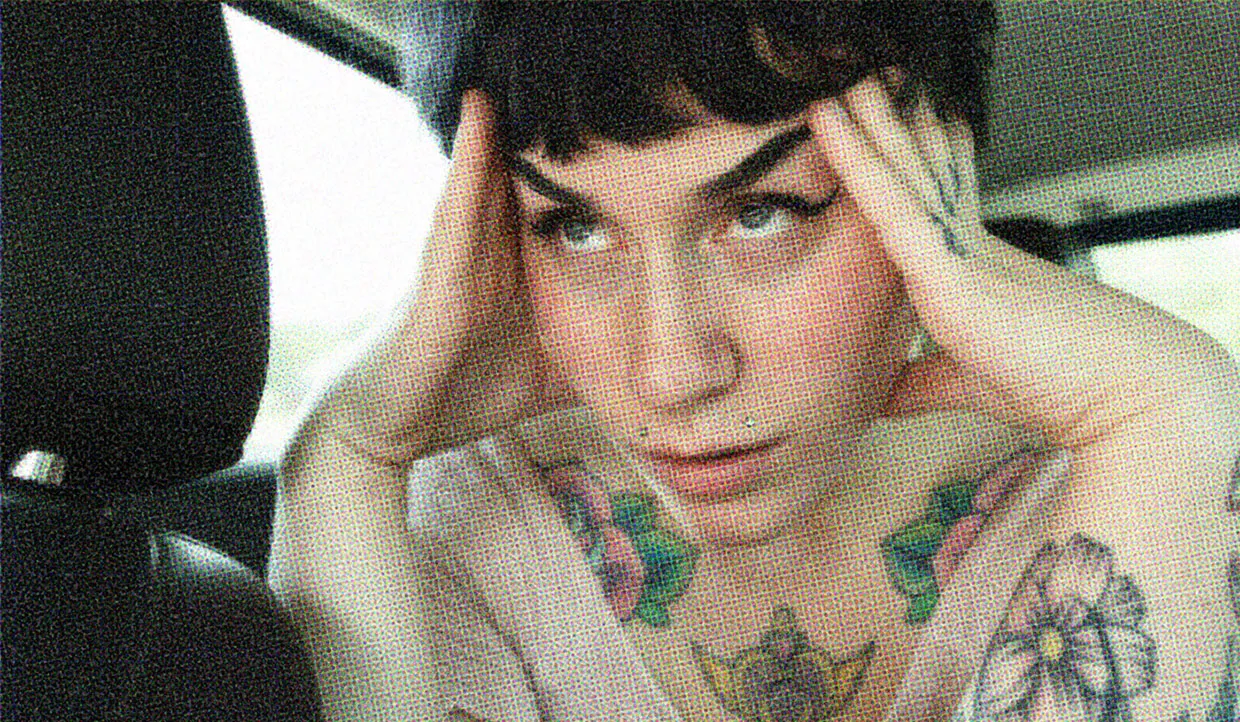 A woman with edgy tattoos looks off into the distance with a distressed look on her face.