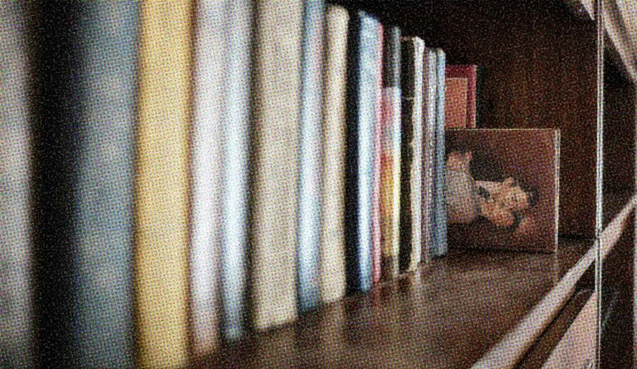 A shelf of books, with one particular book pulled halfway out. The cover hints that it's a romance novel.