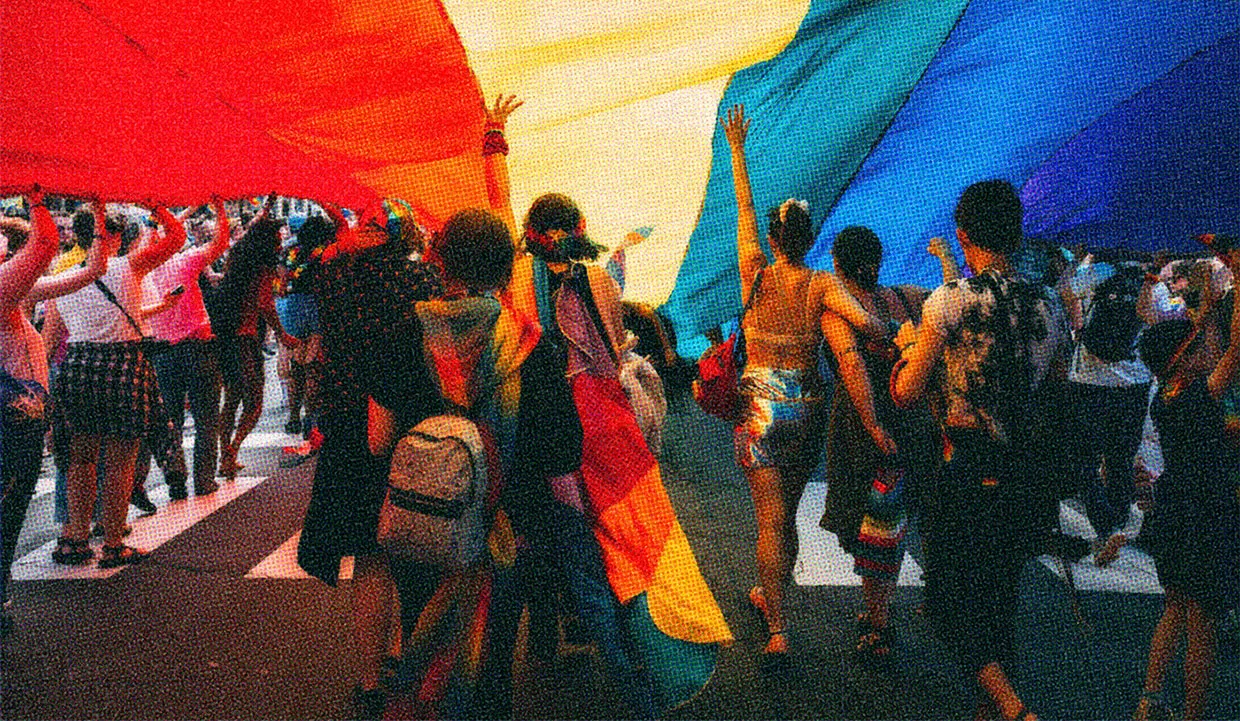 Crowd carrying a rainbow flag during a LGBTQ+ rights march.
