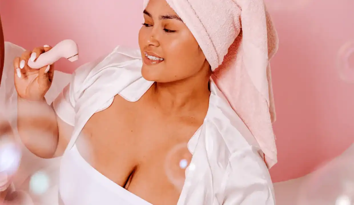 A woman holds a vibrator, looking contemplative. Image courtesy of Girls Get Off.