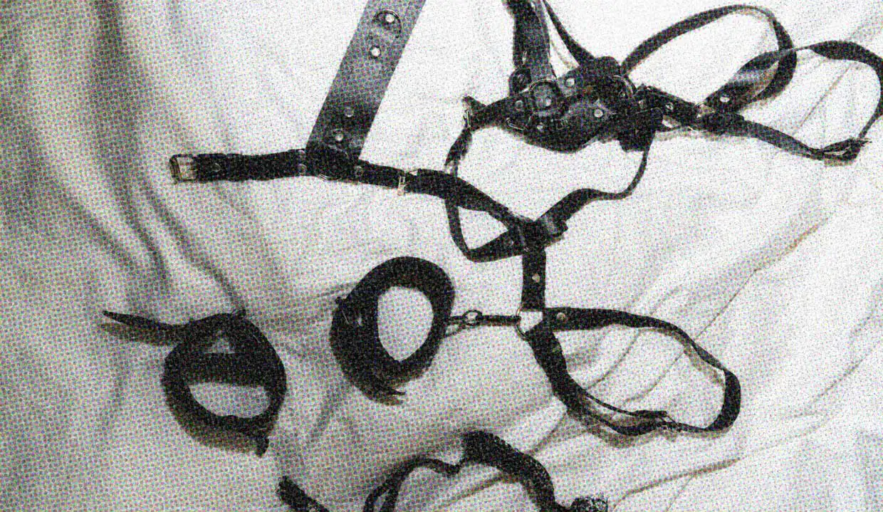 A selection of leather bondage restraints on a bed.