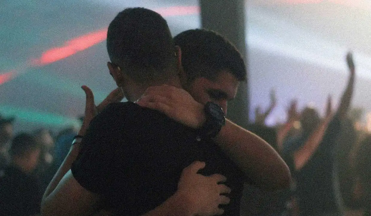 A queer couple embracing at a music festival.
