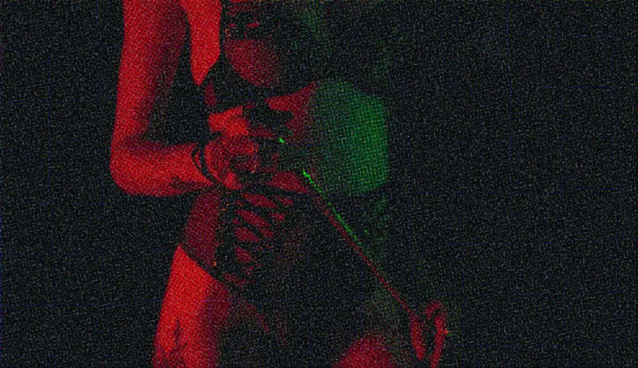 A close-up of a woman's torse, wearing black lingerie, and holding a leather flogger.