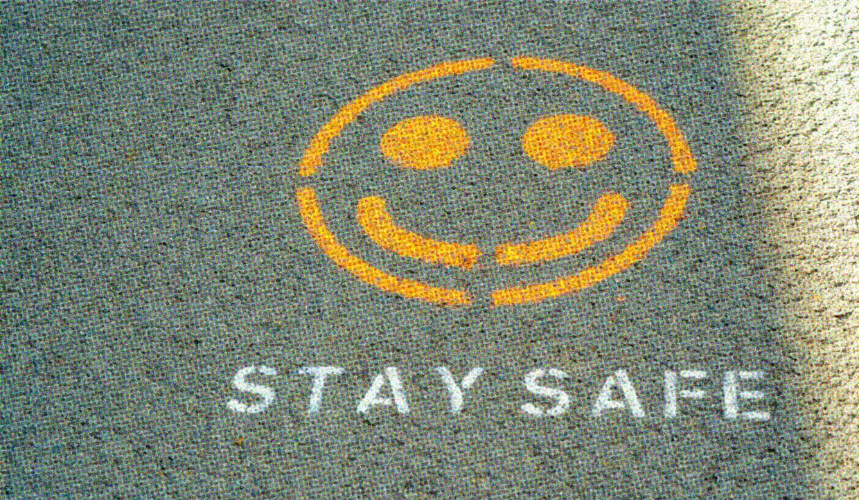A stencil on the pavement shows a yellow smiley face and the words STAY SAFE in white.