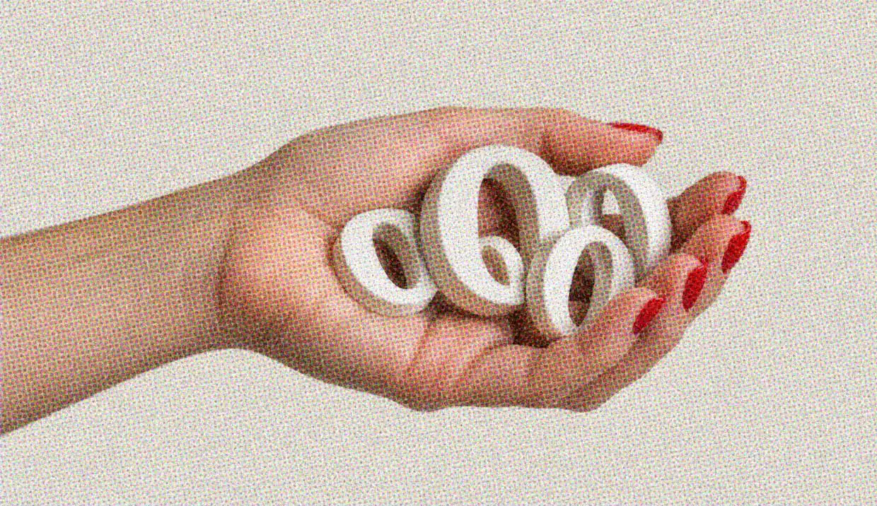 A hand with redi fingernails holds a number of letter Os in the palm.