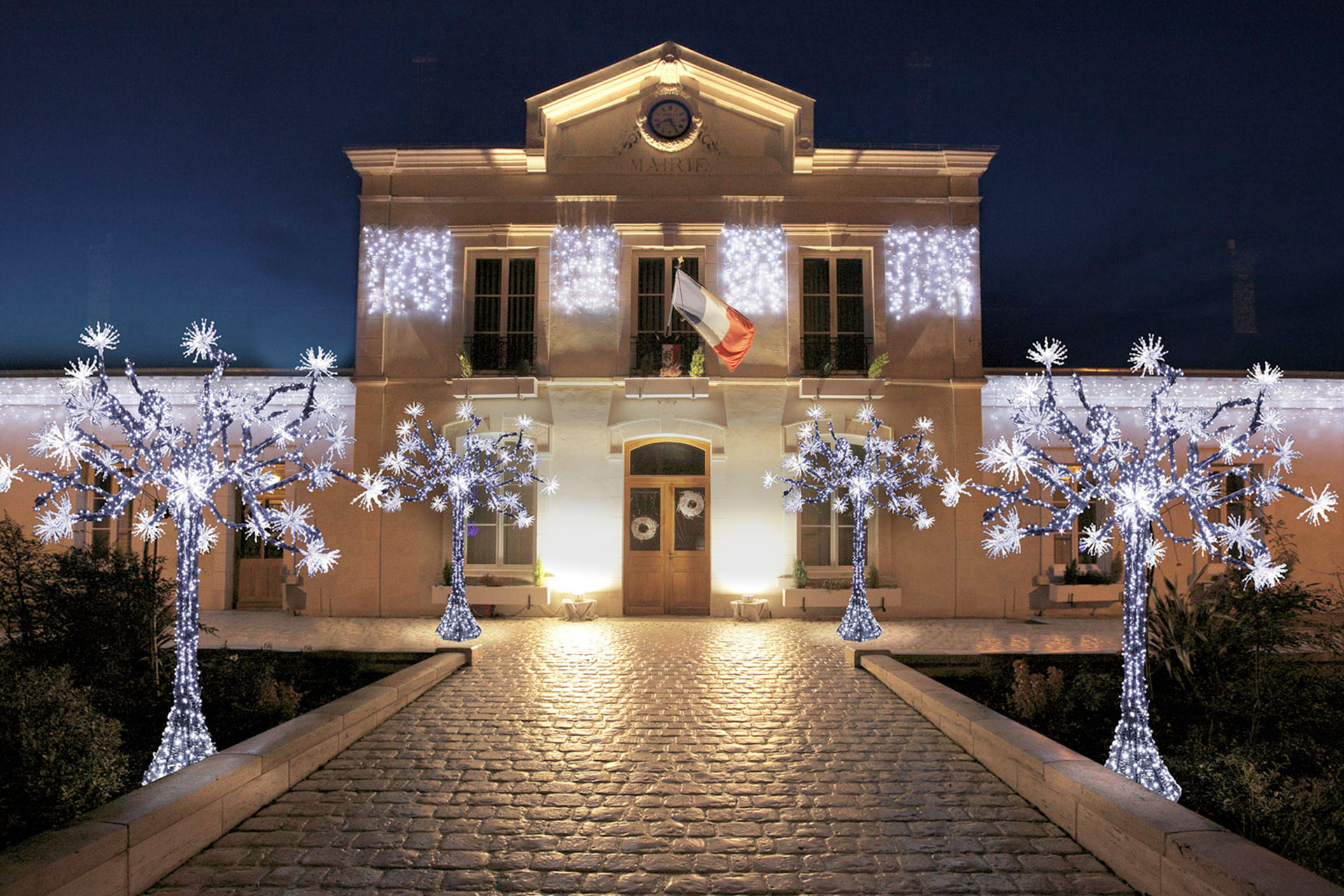 Façade de mairie illuminée la nuit de Noël avec des arbres enveloppés de lumières blanches et installations suspendues