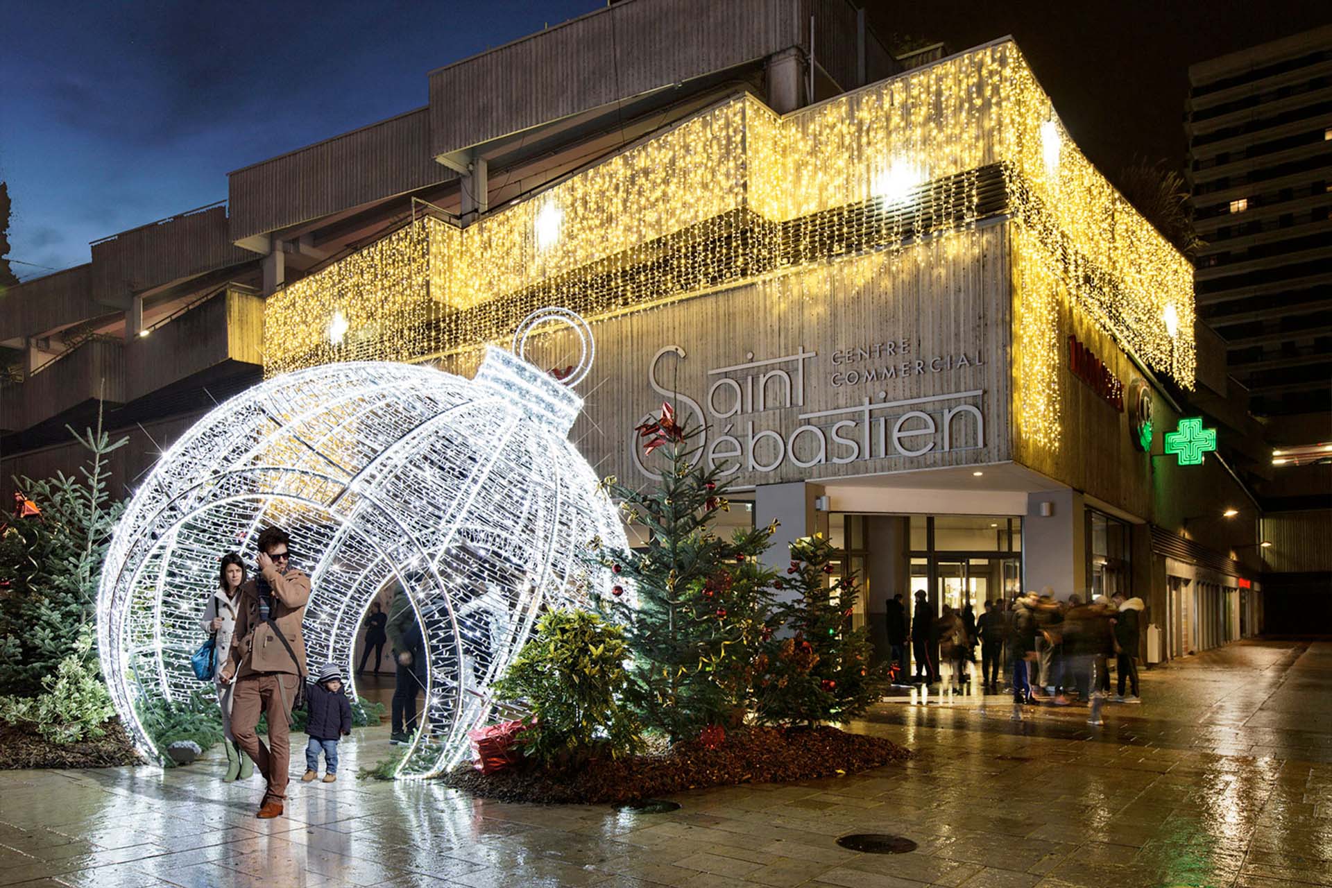 Promeneurs parmi les grandes décorations lumineuses de Noël et guirlandes nocturnes du centre commercial Saint Sébastien, illumination événementielle Wagnon Group