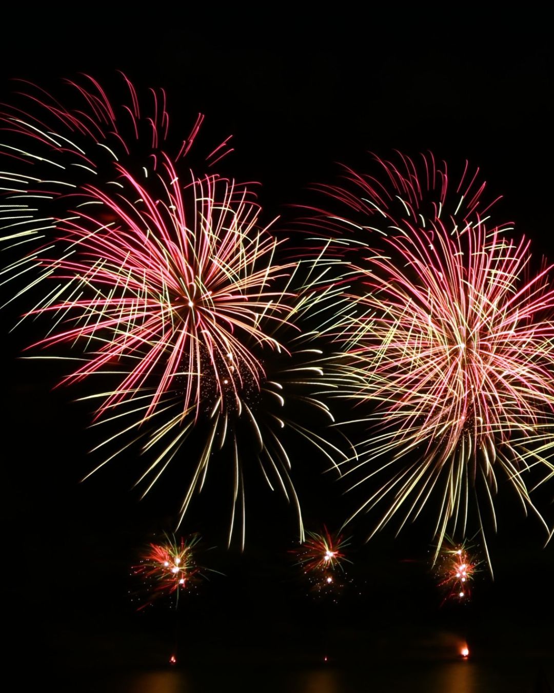 Gerbes de feux d'artifice rose et doré se reflétant sur les eaux du lac de Madine, spectacle pyrotechnique sur mesure Wagnon Group.