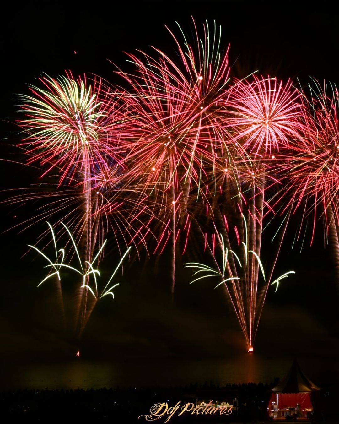 Bouquet de feux d'artifice aux couleurs rose et vert éclatant au-dessus du lac de Madine lors d'un grand spectacle pyrotechnique public réalisé par Wagnon Group.
