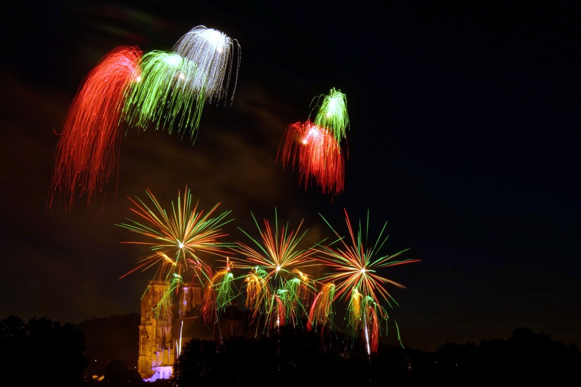 Effets pyrotechniques rouge, vert et blanc en étoile tirés depuis les remparts Vauban de Toul illuminant la cathédrale Saint-Étienne lors de la Fête nationale, spectacle JSE Wagnon Group.