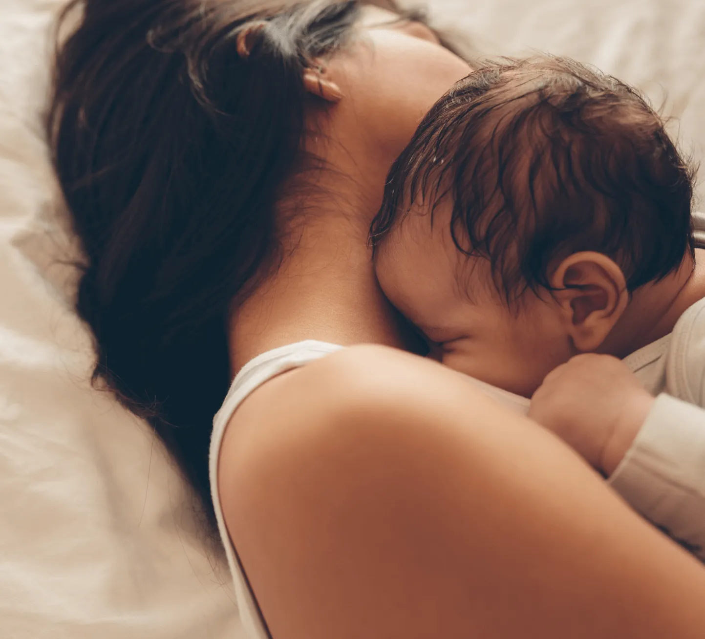 A woman laying on a bed holding a baby.