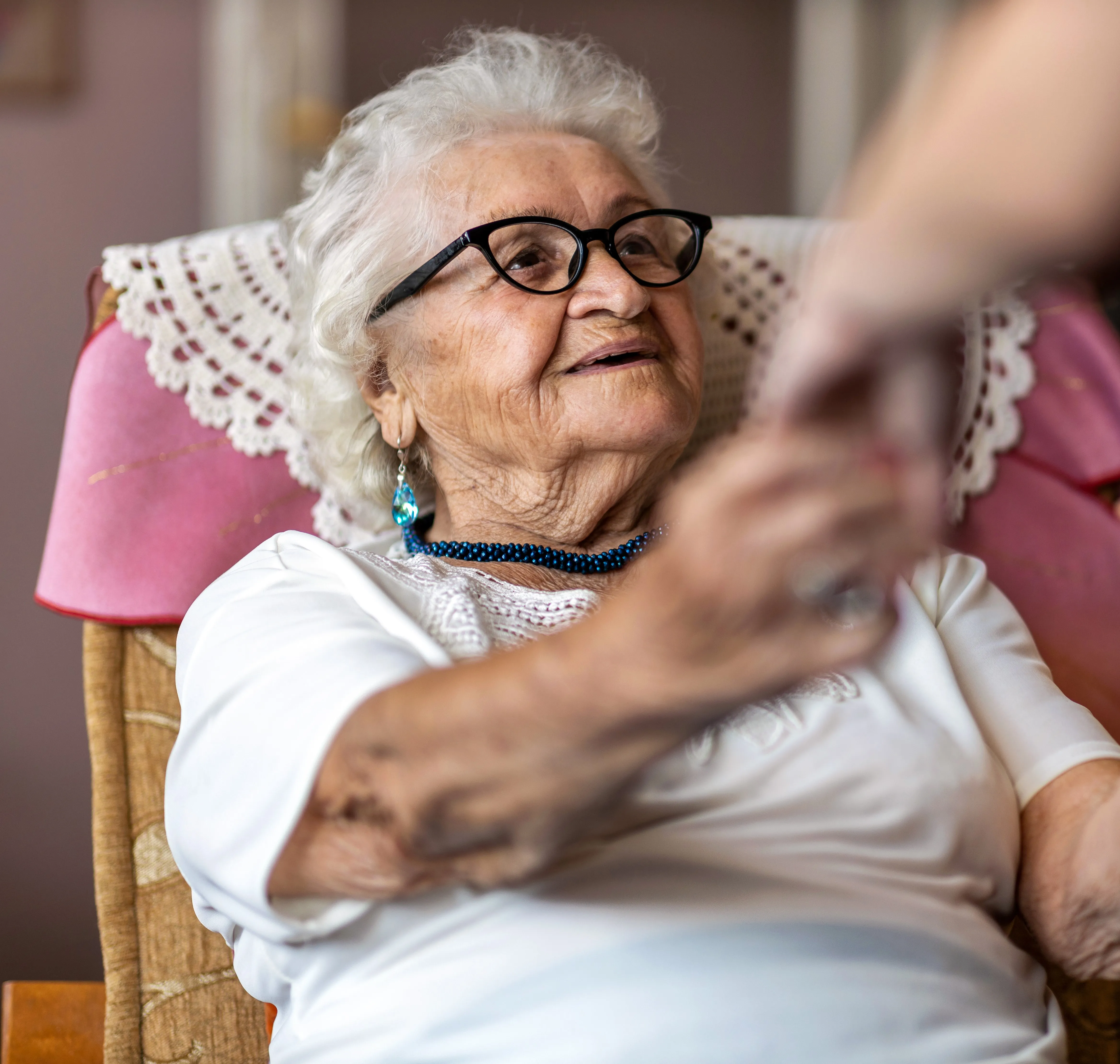 An older woman sitting in a chair holding a remote control.
