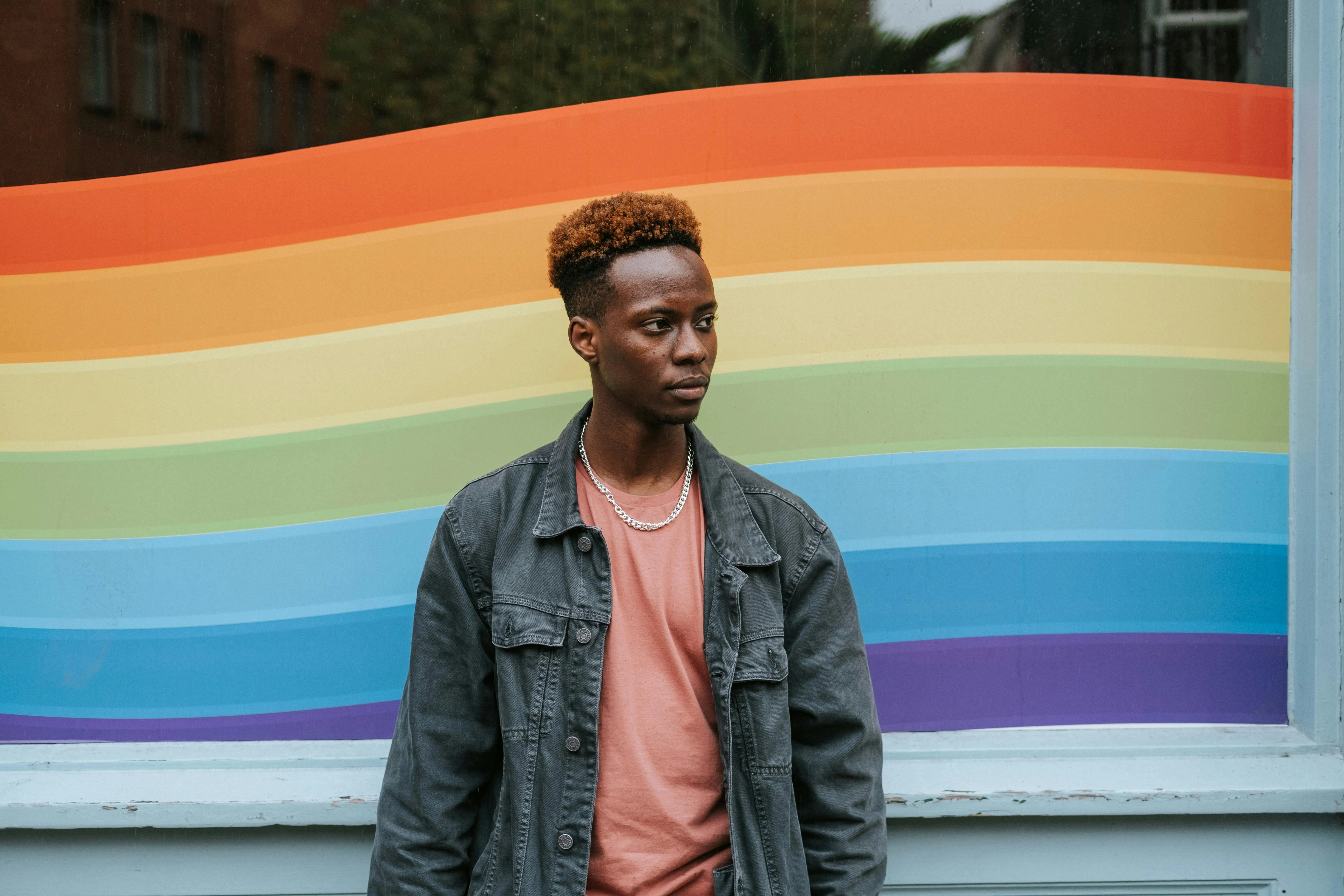 A man standing in front of a rainbow painted wall.