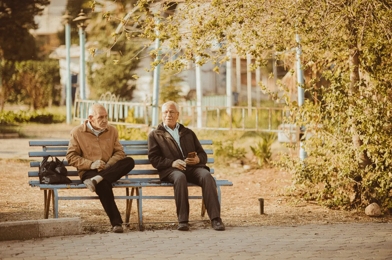 A couple of men sitting on top of a blue bench.