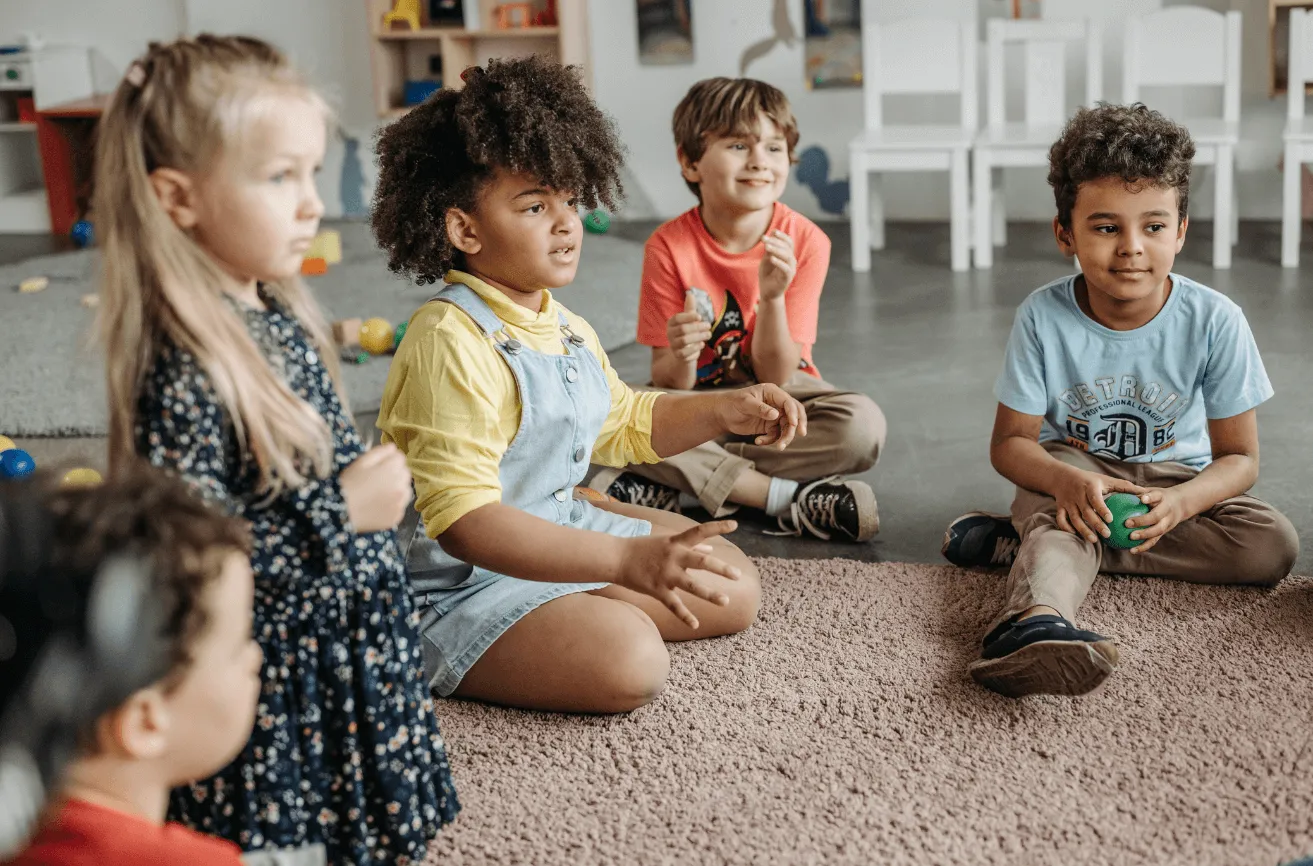 A group of children sitting on the floor in a room.