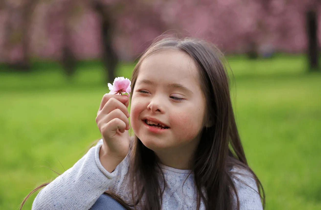 A little girl holding a flower in her hand.