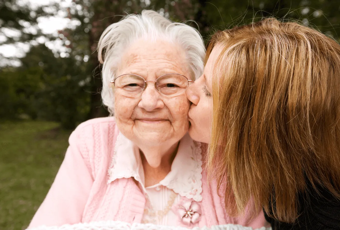 An older woman kissing a younger woman on the cheek.