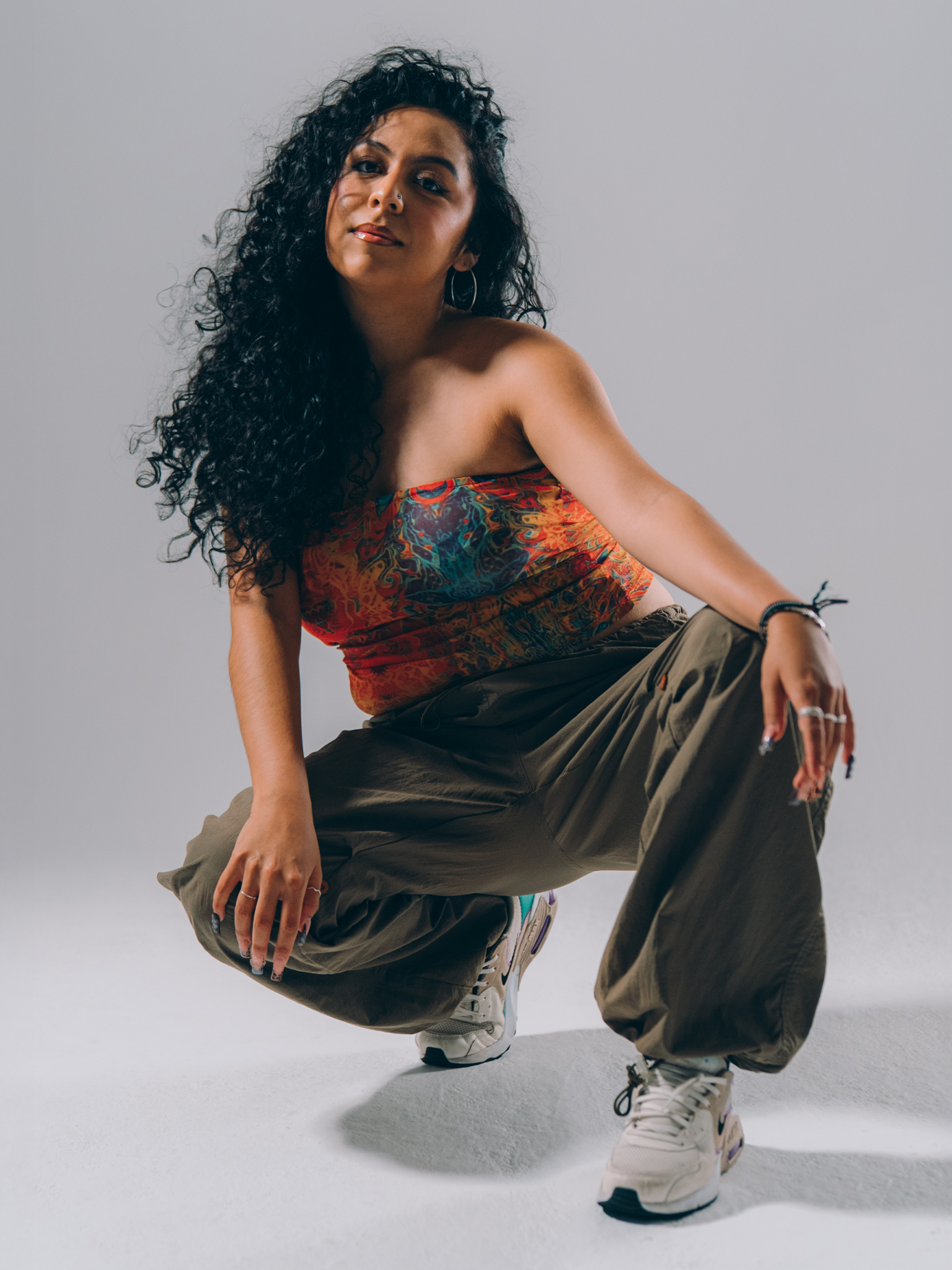 A person sits cross-legged indoors, looking off to the side.