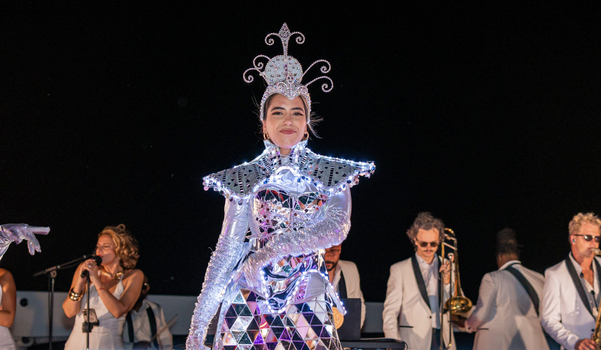 Performer in an illuminated crystal costume on stage with the band