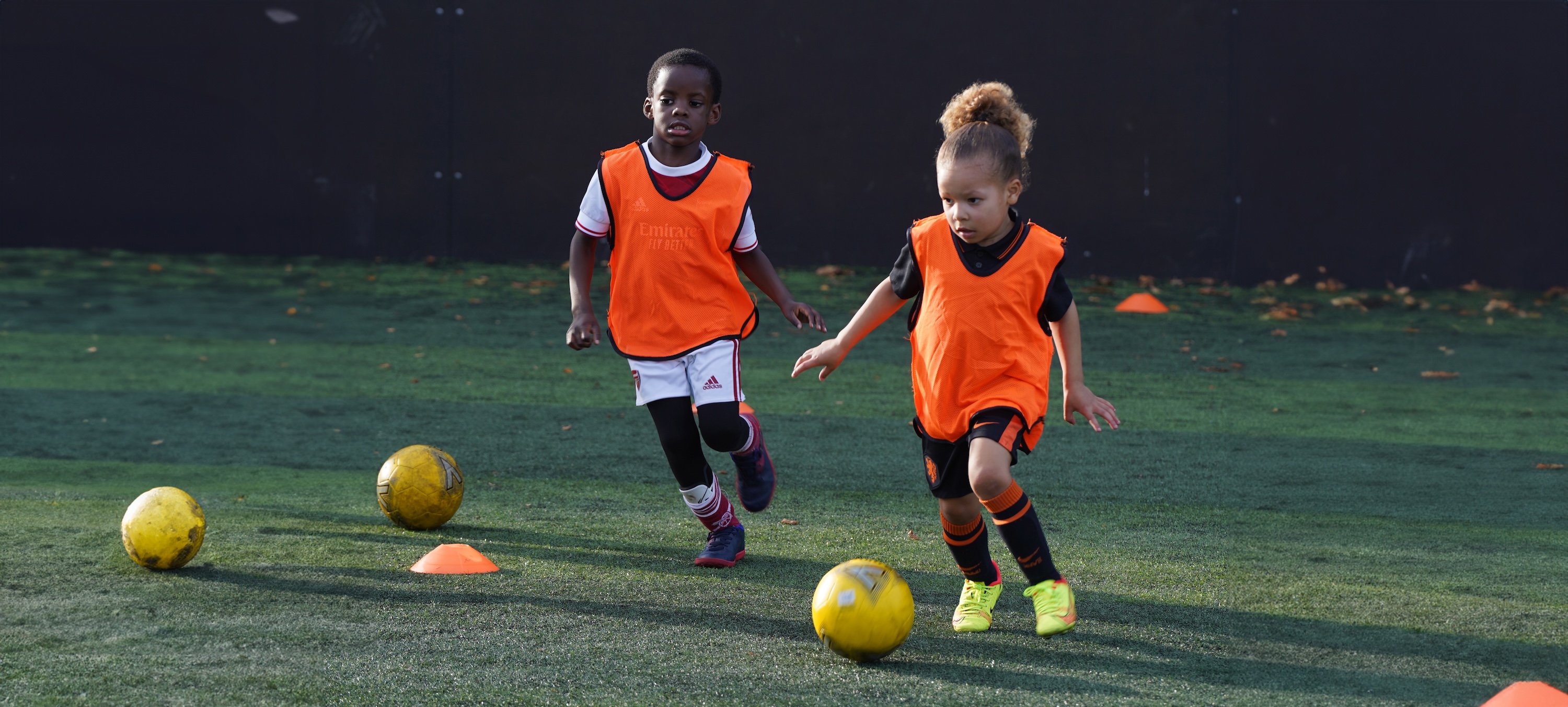 two children playing football together in orange