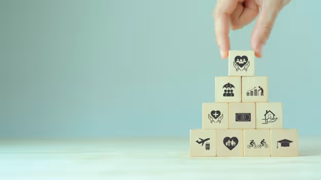 Hand stacking wooden blocks with icons of health, family, money and benefits, symbolizing structured total rewards