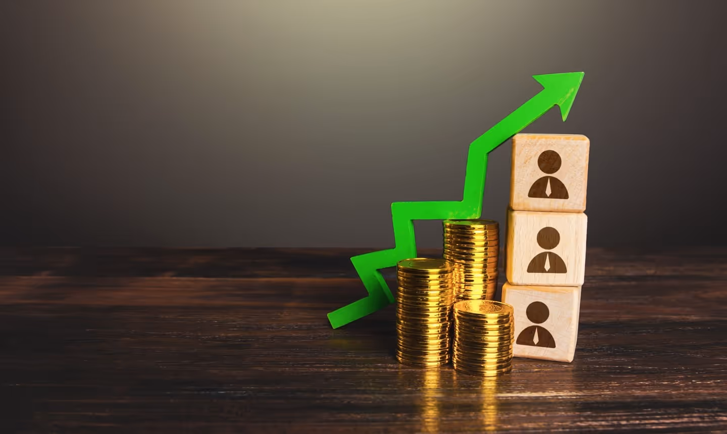 Stacks of coins and wooden blocks with people icons, with a green upward arrow showing growth in workforce value and rewards