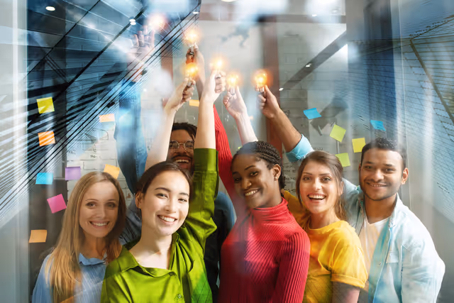 Diverse team raising light bulbs together, representing creativity, innovation and collaborative workplace energy