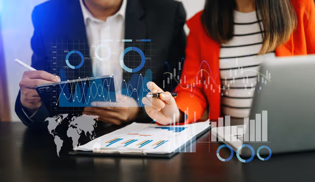 Two professionals reviewing charts on a tablet with digital analytics graphics overlaid on the workspace