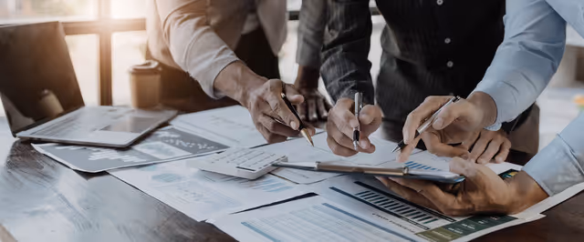 Team collaborating over financial reports and charts during a business planning discussion