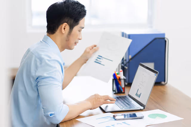 Professional reviewing financial charts on a laptop and analyzing data for business insights