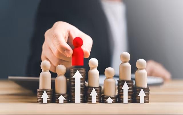 Stacked coins with wooden figures and upward arrows symbolizing employee performance growth and compensation decisions