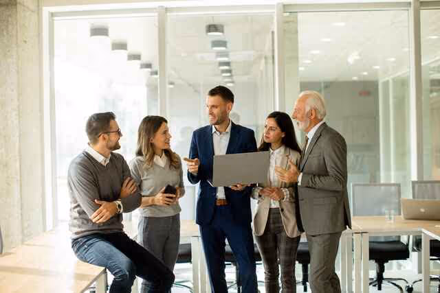 Team of professionals discussing insights together while reviewing data on a laptop