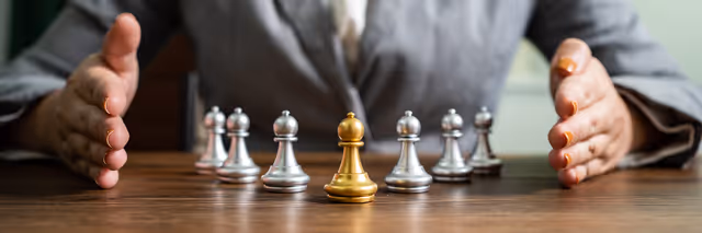 Businessperson framing chess pieces, highlighting strategic leadership and decision-making